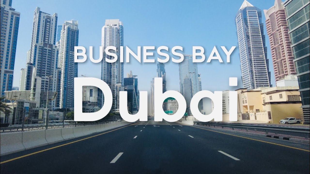 Modern professional working on a laptop with a stunning view of Business Bay skyline, including the Burj Khalifa and canal.