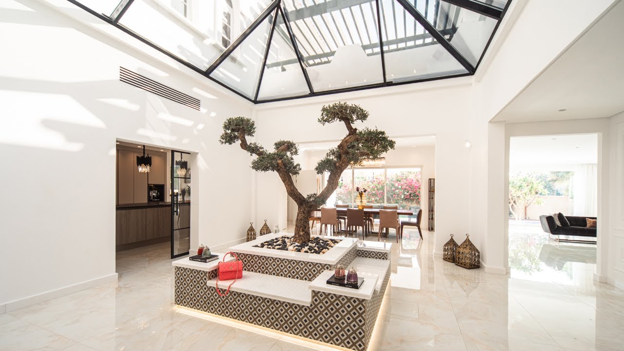 Luxury living room in Dubai with tablet controlling smart home features including lighting, curtains, and climate on a sleek interface