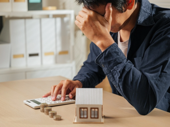 A stressed foreign investor holding a Dubai property contract and a calculator, standing next to a red warning sign, illustrating the top mistakes to avoid when buying property in Dubai, including hidden fees and off-plan delays.
